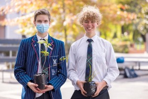 Corin and Toby stand outside holding plants as they smile for a photo.
