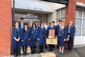 A group of Year 12 students stand outside Senior College holding boxes as they smile for a photo.