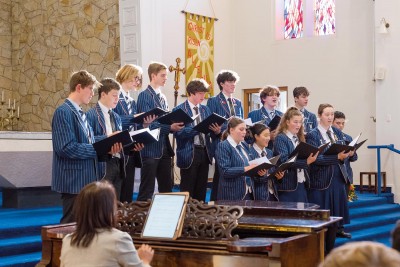 Choir performs in Church as they hold their sheet music.
