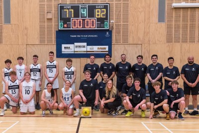 The Old Collegians and Senior St Andrew's basketball teams are photographed as they wear their respective uniforms and stand and crouch in front of the scoreboard from their game.
