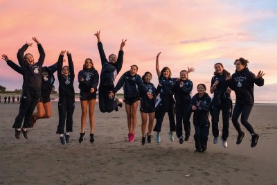 Students jump on the beach at the sunrise ceremony.