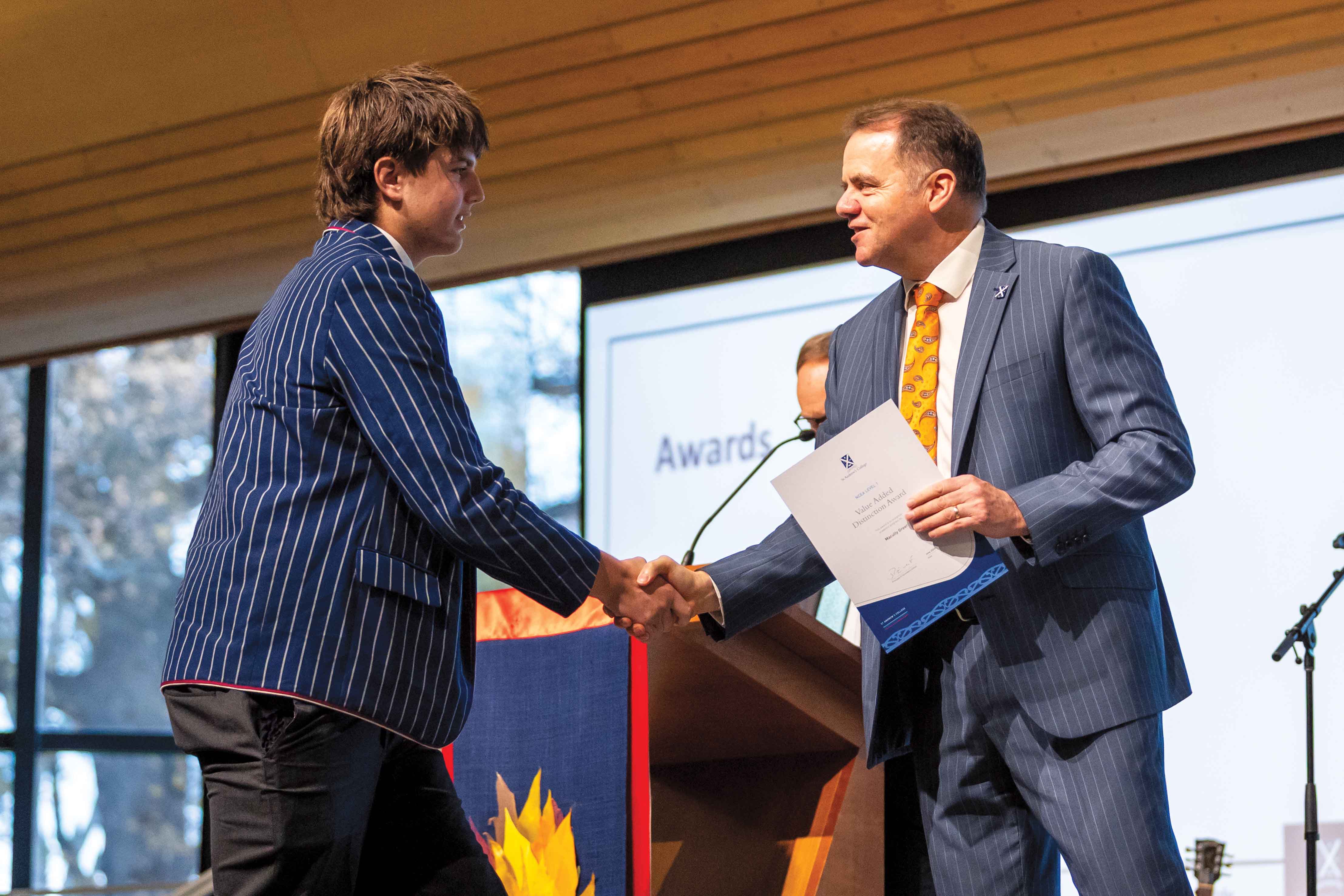 St Andrew's College Year 12 student receiving his Value Added Distinction Award from Rector.