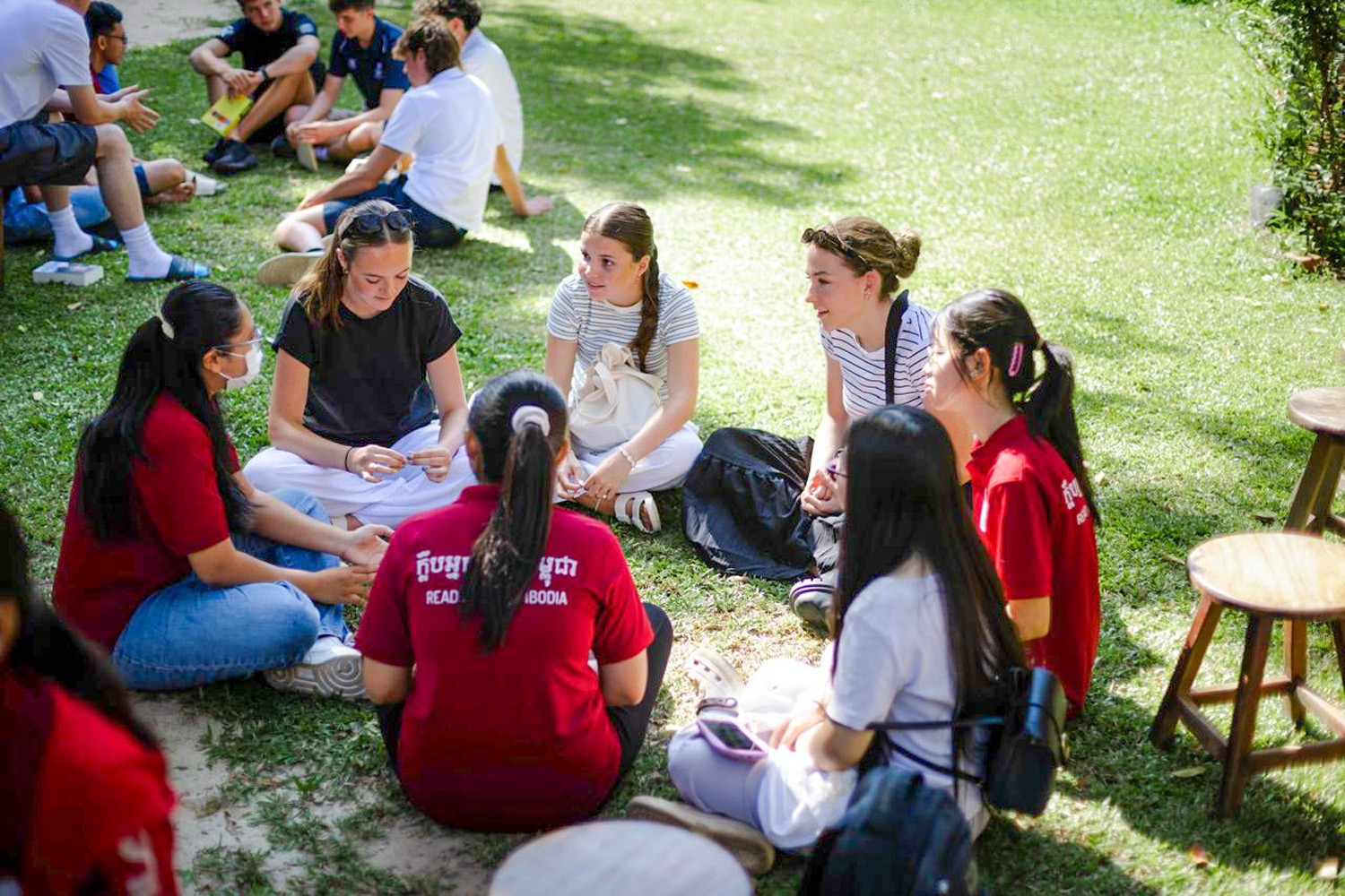 Three St Andrew's College students interacting with Cambodian children
