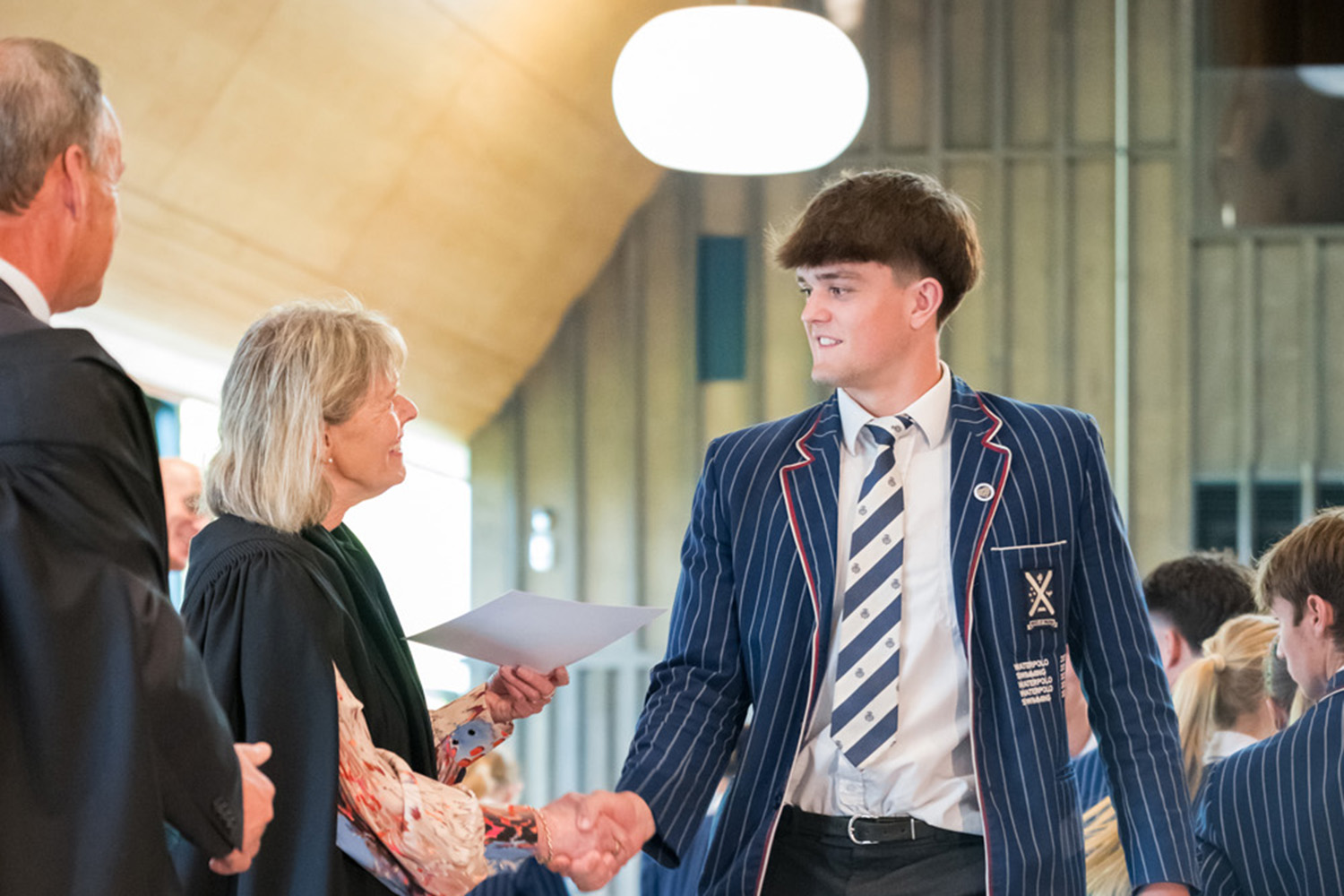 A St Andrew's College student leaver shaking the Rector's hand at Leavers' Assembly.