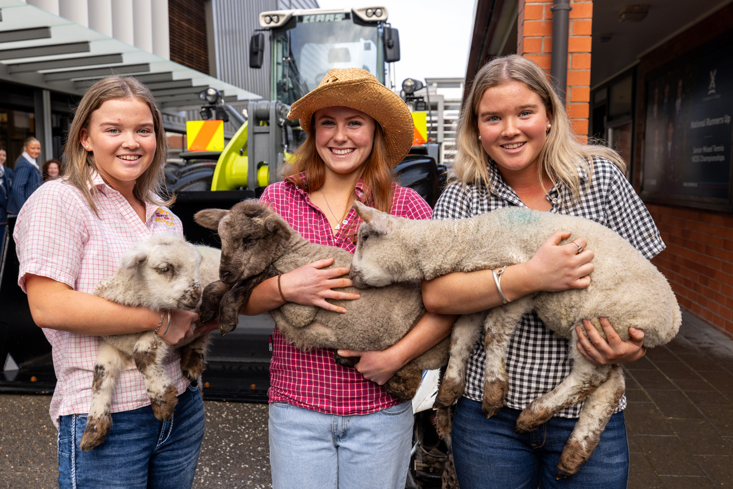 Three St Andrew's College students holding lambs at the 2025 Boarders' Assembly