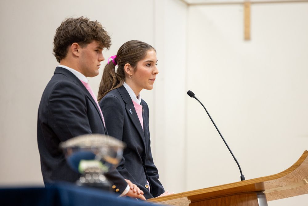 Adolescents at a podium speaking during a St Andrew's College assembly.