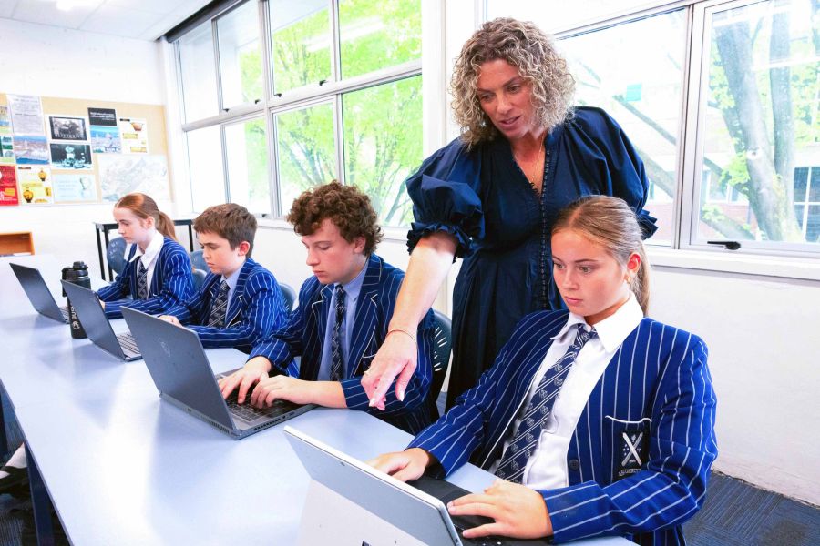 St Andrew's College teacher in classroom with students working on laptops