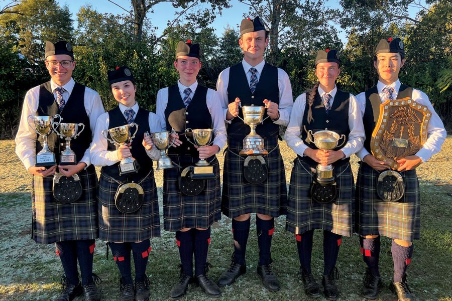 St Andrew's College Pipe Band members holding trophies.