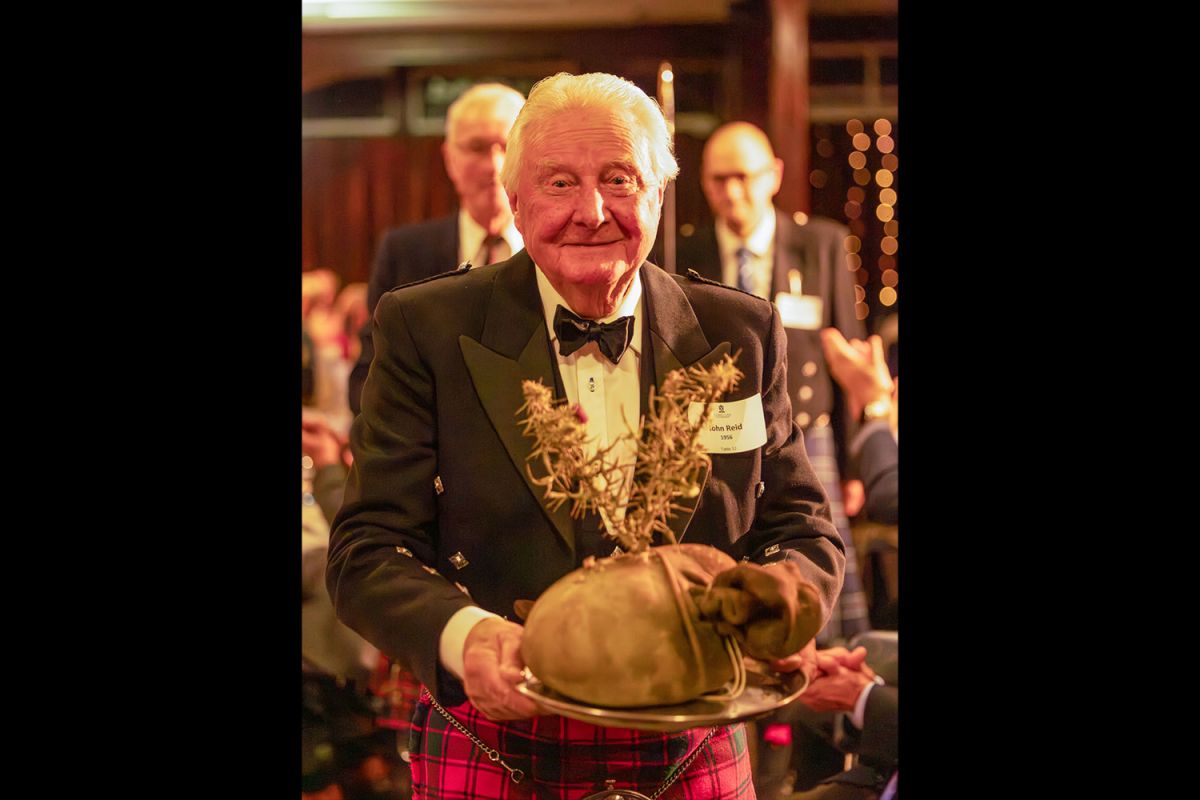 Old Collegian John Reid carrying the traditional haggis