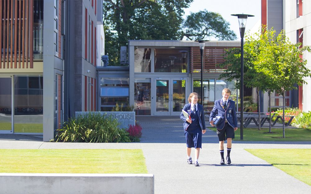 Two students walking outside boarding house.