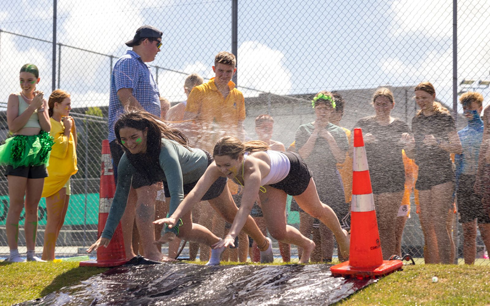 Boarding students enjoying a water slide on a hot day.