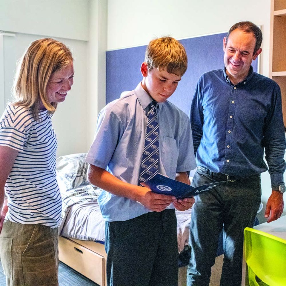 Boarding parents and a student reading welcome booklet.