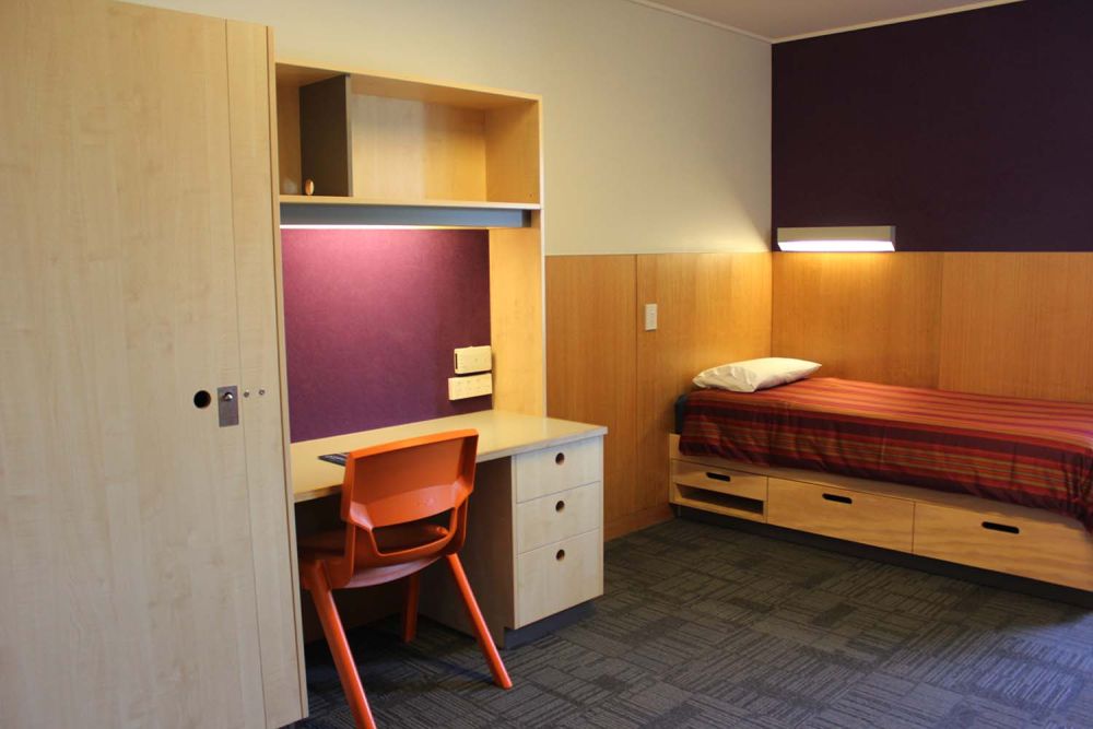 Boarding house bedroom with bed, desk and wardrobe