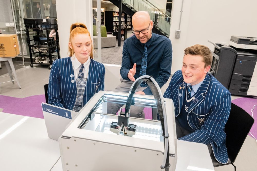 Students in Green Library and Innovation Centre with teacher working on 3D printer