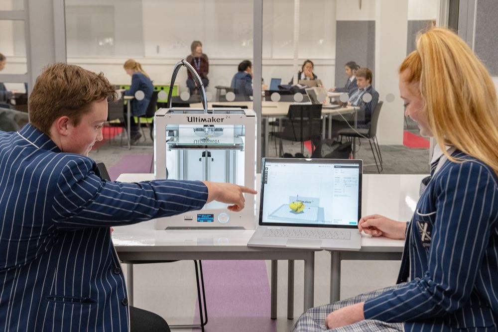 Students in the Green Library and Innovation Centre working on laptop and 3D printer