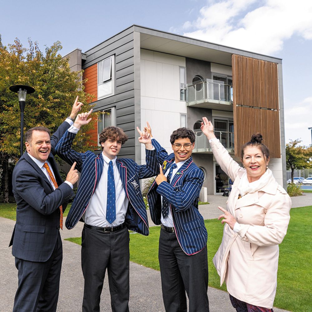 St Andrew's College students, Rector and teacher pointing to the roof of boarding house