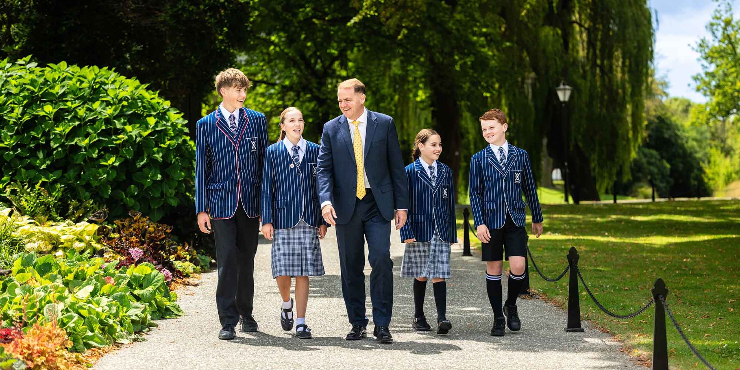 St Andrew's College Rector, Mark Wilson walking and chatting at campus with four students.