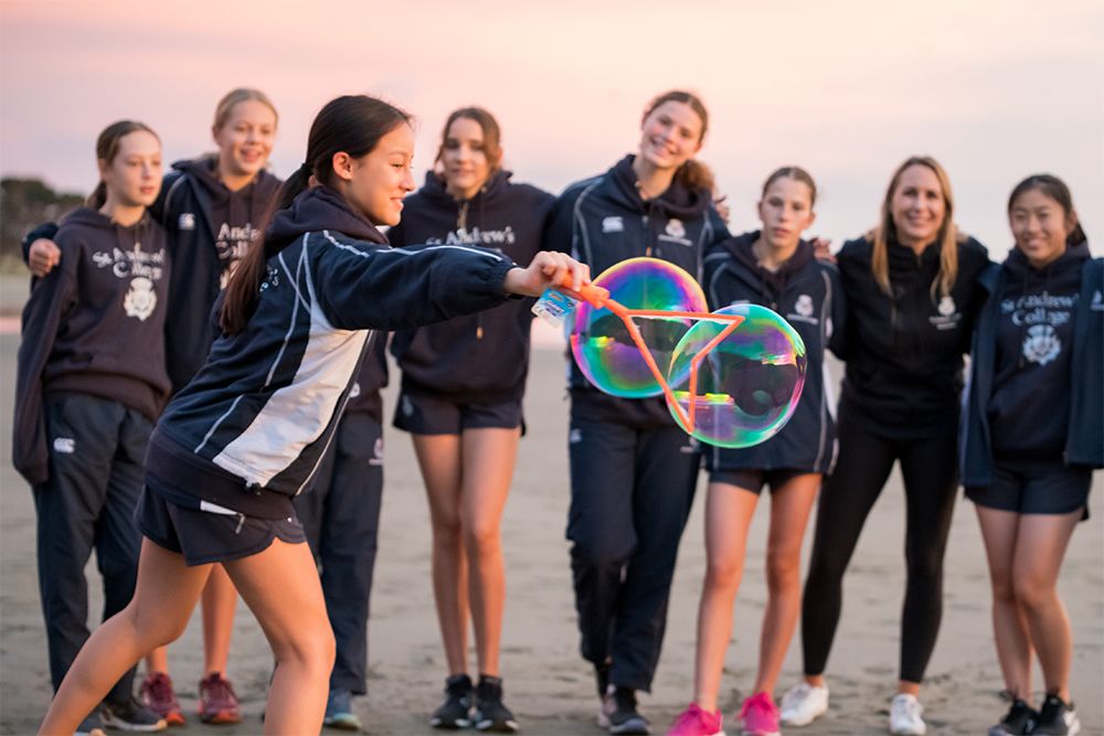 Happy students blowing bubbles at the beach.