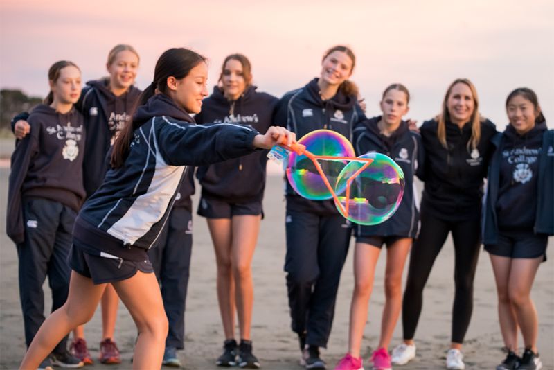 Happy students blowing bubbles at the beach.