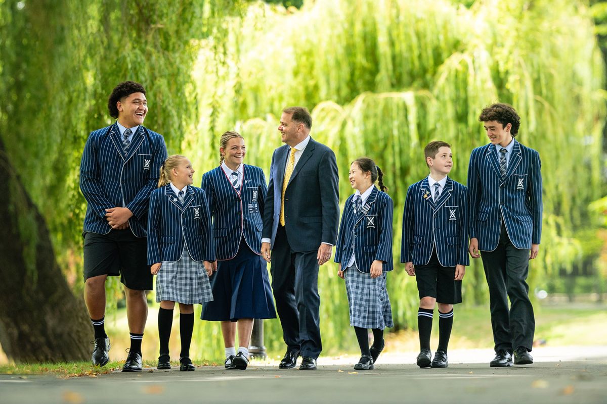 St Andrew's College Rector, Mark Wilson walking at campus and chatting with six students.