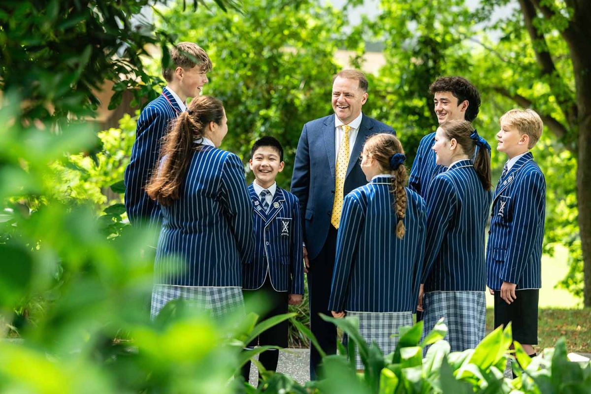St Andrew's College Rector, Mark Wilson chatting with six students.