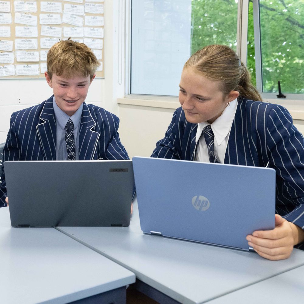 St Andrew's College students in uniform sat at desk with laptops in classroom working