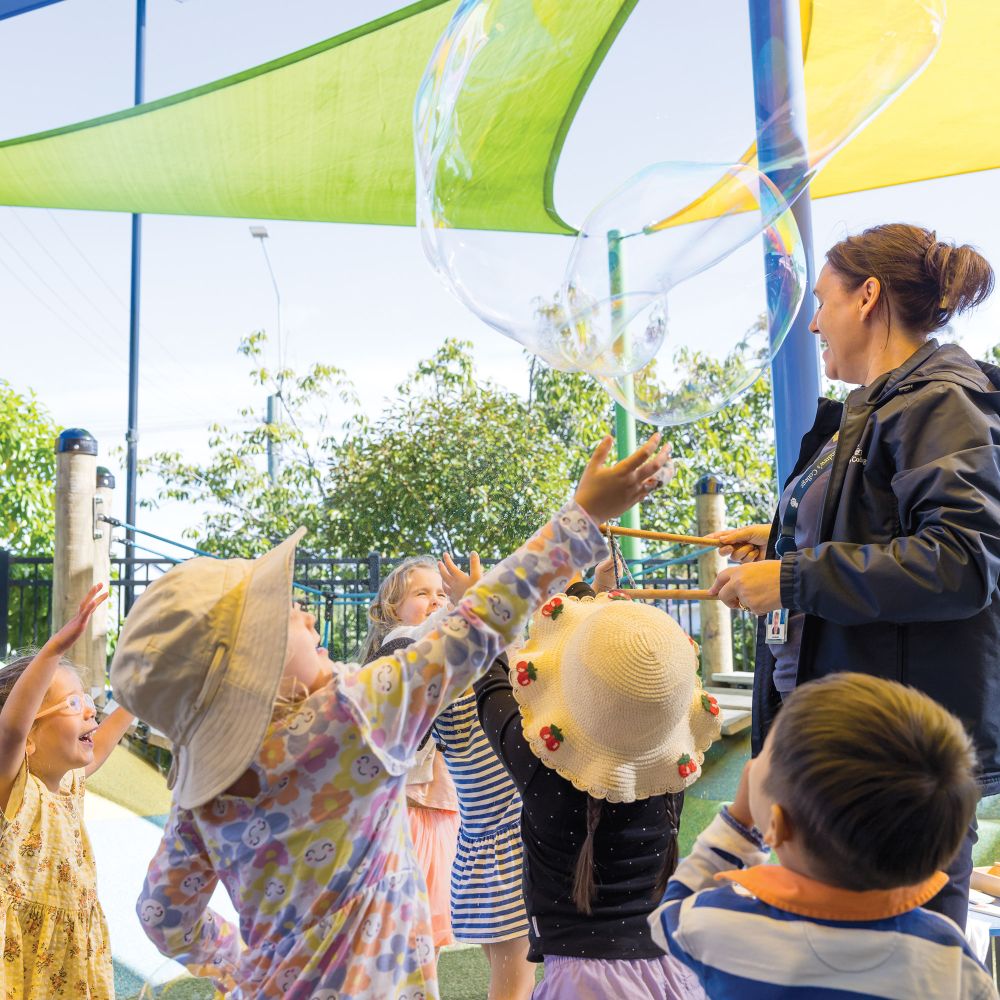 Children playing with bubbles in the pre-school playground.
