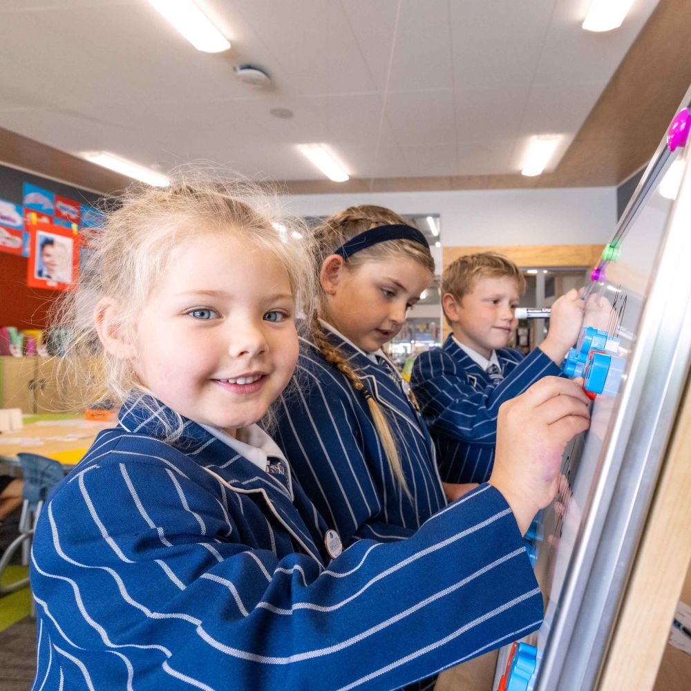 Three St Andrew's College Preparatory School students writing on a whiteboard