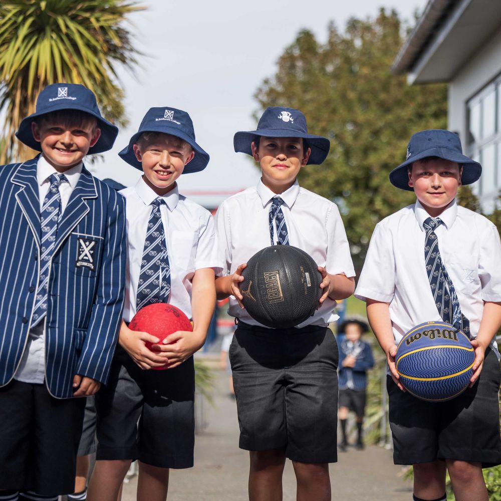 Four St Andrew's College Preparatory School wearing sun hats and holding sport balls outside