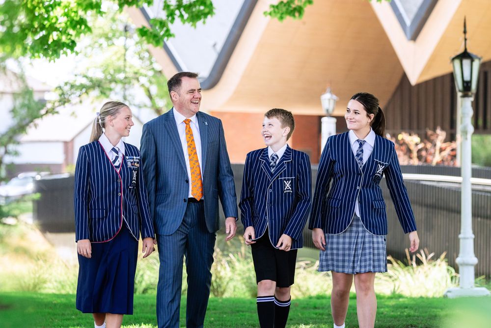 St Andrew's College Rector walking on campus with three students